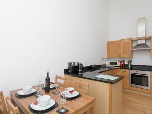 a kitchen with a wooden table with chairs and a dining room at 2 Bed Sea View Apartment with Balcony Parking - Pass the Keys in Benllech