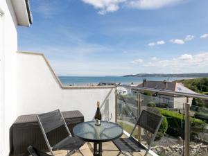 a table and chairs on a balcony with a bottle of wine at 2 Bed Sea View Apartment with Balcony Parking - Pass the Keys in Benllech +32 photos