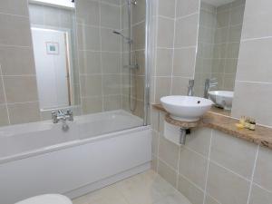 y baño con bañera, lavamanos y ducha. en Pass the Keys 2 Bed Sea View Apartment with Balcony Parking, en Benllech