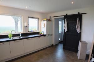 a kitchen with white cabinets and a sink and a window at B&B Hieris't in Hoofdplaat