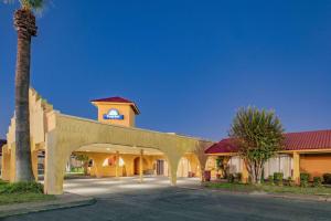 a building with a palm tree and a clock tower at Days Inn by Wyndham Del Rio in Del Rio