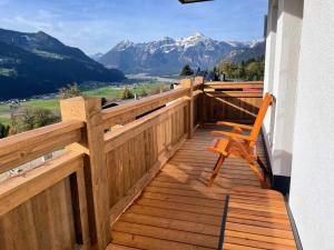 a wooden deck with a chair on a balcony with mountains at Alpenliebe Zillertal in Hart im Zillertal