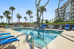 una piscina con sillas azules y palmeras en 6201 Hampton Place, en Hilton Head Island