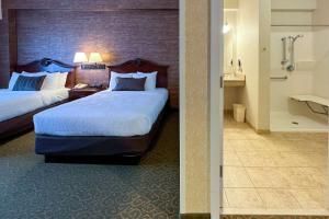 a hotel room with two beds and a bathroom at Maine Evergreen Hotel, Ascend Hotel Collection in Augusta