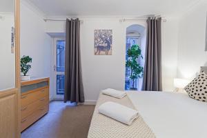 a bedroom with a bed and a dresser and windows at Stay Thames River in London