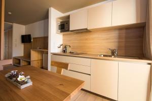 a kitchen with white cabinets and a wooden table at Mölgg Dolomites Residence in San Vigilio Di Marebbe +13 photos