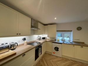 a kitchen with white cabinets and a sink and a dishwasher at Idyllic country cottage near Wells in Wells