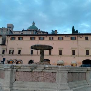 una fontana di fronte a un grande edificio di Appartamenti Santa Chiara ad Assisi