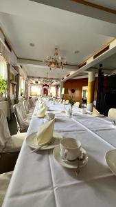 una mesa larga con platos blancos y tazas. en Showhotel Seerose 