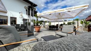 a patio with chairs and a table and umbrellas at Showhotel Seerose in Wolfshain