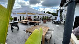 un patio con mesas, sillas y una sombrilla en Showhotel Seerose, 