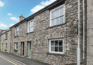 an old stone building with white windows on a street at Greyhound Cottage in Kendal