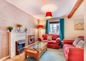 a living room with a fireplace and a red couch at Greyhound Cottage in Kendal