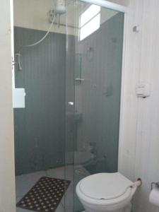 uma casa de banho com um WC e uma cabina de duche em vidro. em CAMPING RECANTO DOS PÁSSAROS em Chapada dos Guimarães
