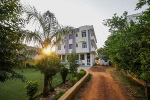 una casa con una palmera frente a un camino de tierra en Hotel Tiger Regency Resort en Sawāi Mādhopur