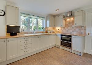 a kitchen with white cabinets and a sink and a window at Avocet House in Langham