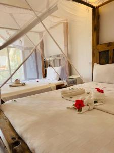 two beds in a room with flowers on them at Babalao Bungalows in Nungwi +37 photos