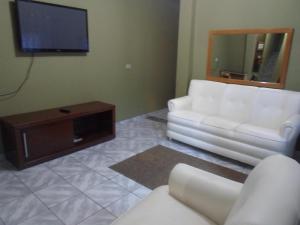 a living room with white furniture and a flat screen tv at Lima hospedagem caseira in Olímpia