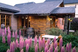 a wooden cabin with pink flowers in front of it at Kau Kaleshen in El Calafate