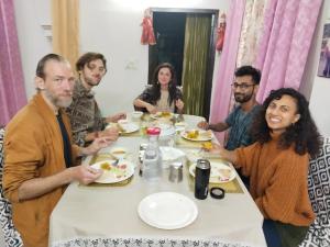 eine Gruppe von Menschen sitzt um einen Tisch herum und isst in der Unterkunft Gungun Homestay in Rishikesh + 13 Fotos