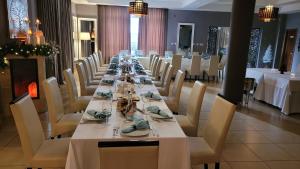 uma mesa longa num restaurante com mesas e cadeiras brancas em Vila Roca Hotel and SPA em Valea Drăganului