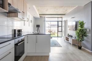 a kitchen with white cabinets and a large window at Condo at Woodstock Quarters - Stylish 2 ensuite Bedroom Apartment with Spacious Balcony in Cape Town