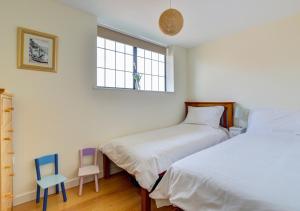 a bedroom with two beds and a chair and a window at Flat 8 Broadleys in Swanage