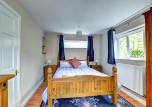 a bedroom with a wooden bed with blue curtains at The Smokery in Swanage