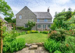 a stone house with a garden in front of it at Rainbow Cottage in Long Bredy