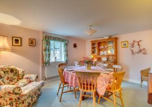 a dining room with a table and chairs and a couch at Rainbow Cottage in Long Bredy
