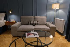 K23 Color Suites في أثينا: غرفة معيشة مع أريكة وطاولة زجاجية