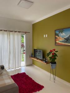 a living room with green walls and a red rug at P&M'S Porto Seguro Taperapuan in Porto Seguro