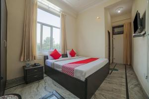 Un dormitorio con una cama con almohadas rojas y una ventana en Hotel Tiger Regency Resort en Sawāi Mādhopur