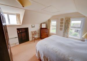 a bedroom with a bed and two windows and a chair at Cornerways in Worth Matravers