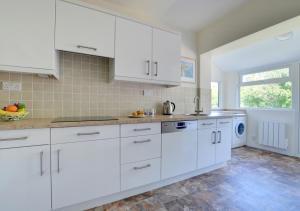 a white kitchen with white cabinets and a window at Cornerways in Worth Matravers