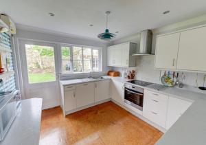 a kitchen with white cabinets and a large window at Wild Hill in Worth Matravers