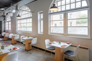 a restaurant with white tables and chairs and windows at KM Hotel in Edinburgh