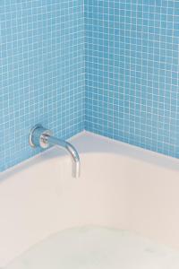 a bathroom with a tub and a blue tile wall at Hotel de Milliano in Breskens