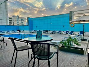 een patio met een tafel en stoelen en een zwembad bij Copthorne Hotel Sharjah in Sharjah