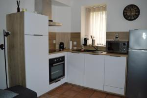 cocina con armarios blancos y nevera en Les volets bleus - duplex proche plage et centre en Arromanches-les-Bains