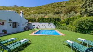 a swimming pool in a yard with two blue chairs at El Encinar Antequera - La Joya by Ruralidays in Antequera