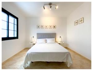 a white bedroom with a large bed and two tables at Villa Córdoba in Playa Blanca