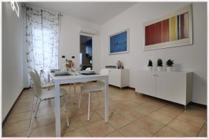 uma sala de jantar branca com uma mesa e cadeiras brancas em [10 min metro] Palavela Suite em Turim