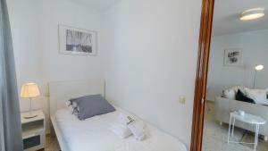 a bedroom with a white bed and a mirror at Apartamento Almijara Cómpeta by Ruralidays in Cómpeta
