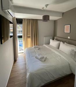 Un dormitorio con una gran cama blanca y una ventana en Niarchos apartment III, en Atenas