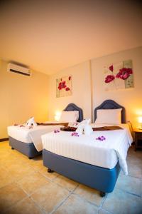 Dos camas en una habitación de hotel con flores. en Rico's Patong Hotel, en Patong Beach
