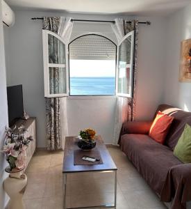 a living room with a couch and a table and a window at Estudios Costavigía Mazagón by Ramona in Mazagón