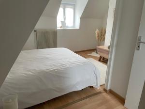1 dormitorio con cama blanca y ventana en Maison de ville avec parking gratuit, en Chablis