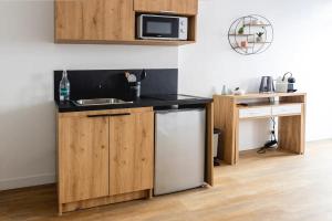 a kitchen with wooden cabinets and a sink and a microwave at Studio cosy Pinot Meunier au cœur d'Hautvillers in Hautvillers