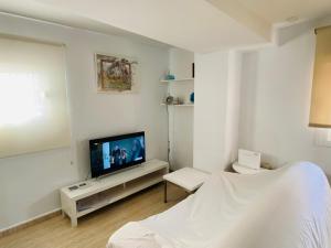 a white room with a bed and a television at Ático Cádiz Playa in Cádiz